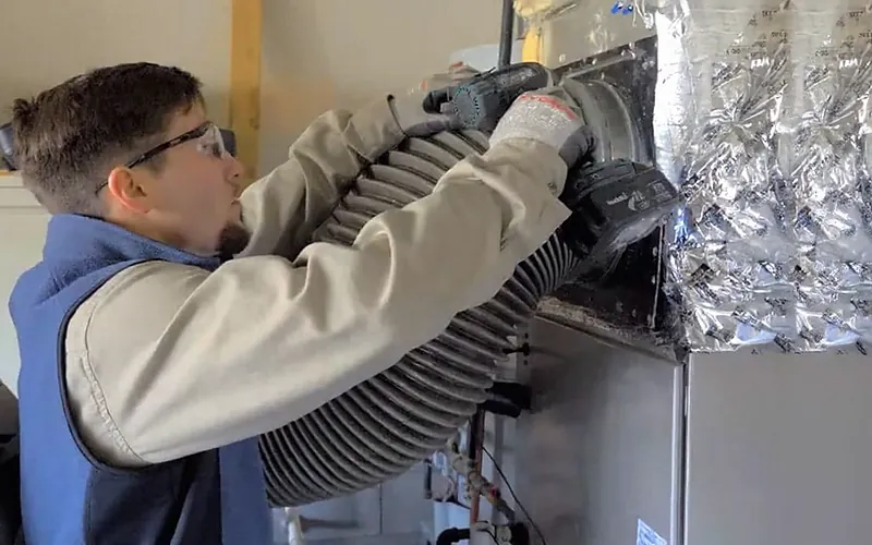 Sanmor HVAC Solutions technician connecting insulated flexible duct to a new indoor unit